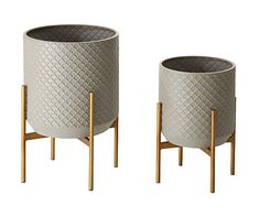 two round planters with wooden legs are shown in front of a white background, one is grey and the other is beige