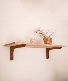 a wooden shelf with two vases and a basket on it next to a wall