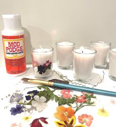 several candles and some flowers on a table with a pencil next to one candle in the middle