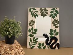 a decorative mirror sitting on top of a table next to a potted green plant