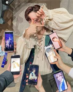 a group of people holding up cell phones in front of each other with pictures on them