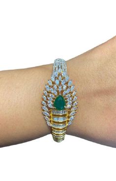 "Discover an exquisite gold-plated bracelet featuring intricate designs and stunning emerald green stones. This openable diamond bracelet, also known as a Pakistani kada or bangle, combines the elegance of CZ with traditional craftsmanship. Perfect for adding a touch of luxury to any outfit." Our products are meticulously handcrafted, ensuring each piece is unique. Due to the manual craftsmanship, you may notice slight irregularities, which are natural and do not compromise the quality of the jewelry. Gold Plated Diamond Bangle For Wedding, Wedding Gold Plated Diamond Bangle Bracelet, American Diamond Bracelet For Gift, American Diamond Bangle Bracelets As Gift, Gold Bracelet With American Diamond, Round Shape, Gold Bangle Bracelet With American Diamonds, Gold American Diamond Bangle Bracelet, Festive Cubic Zirconia Bangle Bracelets, Gold Cubic Zirconia Bracelet For Festive Occasions