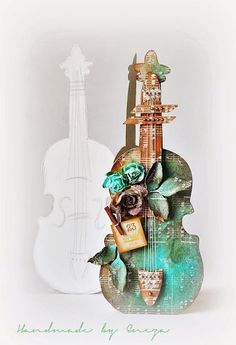 a violin is sitting on top of a green vase with flowers and other items around it