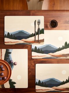 three placemats with mountains and trees on them