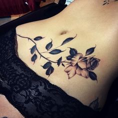 a woman's stomach with a rose tattoo on her chest and black lacy bra