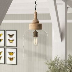 a light fixture hanging from the ceiling in a room with pictures on the wall behind it