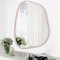 a mirror sitting on top of a dresser next to a vase with flowers