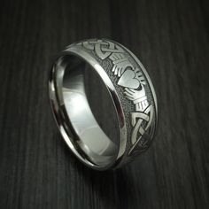 This Titanium ring features: - A Stipple and Polish Finish - A Claddagh Celtic Design - A Domed Design - 8mm Width Our Titanium rings will not tarnish or cause your skin to discolor. This ring can be fully customized! If you need to change any aspect of the ring, please contact us and we can help you out! If you have any other questions at all, please let us know! All rings will come with our standard Logo engraved on the inside of the ring. (Except for rings with wood sleeves) Buy with confiden Classic Silver Titanium Rings, Classic Titanium Ring With Polished Finish, Classic Titanium Jewelry For Gifts, Engraved Stainless Steel Promise Ring, Stainless Steel Ring With Polished Finish For Promise, White Gold Engraved Ring In Stainless Steel, Symbolic Promise Rings With Polished Finish, Classic Titanium Jewelry For Wedding, Classic Titanium Wedding Jewelry