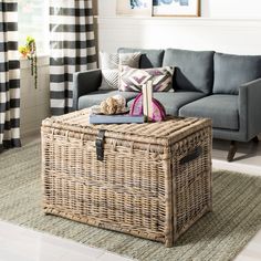 a wicker trunk sitting on top of a rug in front of a gray couch