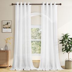 a white curtain hanging in front of a window next to a potted green plant