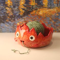 a red bowl with yarn in the shape of a crab sitting on top of it