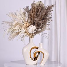 a white vase with some brown and white flowers in it