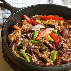 a skillet filled with meat, peppers and onions