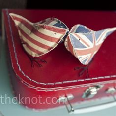 two small birds are sitting on top of a red suitcase with an american flag design