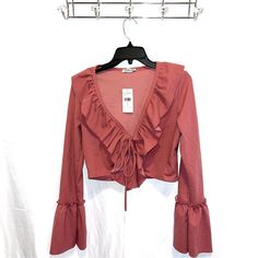 Stand Out In A Sophisticated Number With This Long-Sleeved Ruffle Frill Top. Featuring A Plunge Neckline With Tie Detailing, This Sassy Crop Is The Perfect Choice For A Classy Night Out. Pair With A Bodycon Midi Skirt And Heels To Complete The Elegant Look. Rose Pink / Mauve Pink Long Sleeve Ruffle/Frill Details Around Neckline And On Sleeves Cropped Plunge Neckline Tie Feature On Bust 96% Polyester 4% Spandex Flirty Long Sleeve Blouse For Spring, Fitted Ruffle Top For Brunch, Flirty Ruffled Tops For Fall, Spring Night Out Blouse With Ruffle Hem, Flirty Fitted Blouse For Fall, Spring Ruffle Hem Blouse For Night Out, Party Long Sleeve Top With Ruffle Hem, Fitted Flirty Blouse For Fall, Party Tops With Ruffle Hem And Long Sleeves