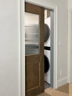 an open door leading to a washer and dryer in a room with white walls