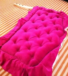 a fuchsia colored mattress is laying on a bed with an orange and white striped bedspread