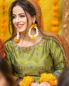 a woman in a green dress with flowers on her head and yellow garland around her neck