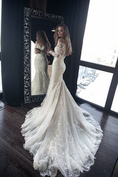 a woman standing in front of a mirror wearing a wedding dress