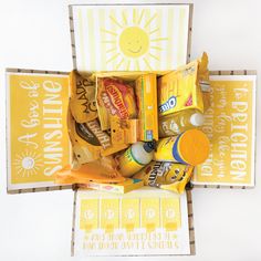 a box filled with snacks and candy sitting on top of a white table next to a yellow sign