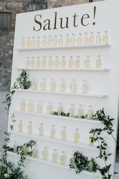 a sign that says salute on it with bottles and greenery in front of it