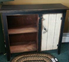 an old wooden cabinet with two doors and a rug on the floor next to it