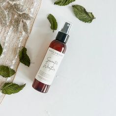 a bottle of body lotion sitting on top of a table next to some leaves