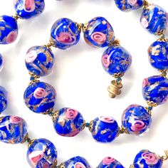 Vintage choker necklace of Murano Venetian art glass beads. The Sommerso type beads are clear glass with cobalt blue, pink roses and Aventurina (copper color) swirls. It's incredibly lovely to look at and to wear. Venetian glass beads have filigree end caps. They are knotted with copper and blue colored cord. Choker fastens with a screw barrel clasp. In original condition. Circa 1950s. See all ten views. Era: 1900s, Mid century Measurements: Length 16.5 inches ( cm), Beads are 14mm in diameter. Blue Murano Glass Beaded Necklace With Large Beads, Blue Murano Glass Necklace With Polished Beads, Blue Single Strand Murano Glass Beaded Necklace, Handmade Blue Murano Glass Beaded Necklaces, Blue Murano Glass Jewelry With Colorful Beads, Blue Single Strand Murano Glass Necklace, Blue Murano Glass Single Strand Necklace, Blue Murano Glass Round Jewelry, Copper And Blue