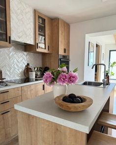 a bowl filled with flowers sitting on top of a kitchen counter