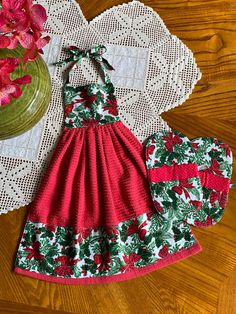 a red and green dress sitting on top of a table next to a potted plant