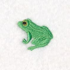 a green frog sitting on top of snow covered ground