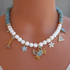 🌟 Discover the Beauty of Our Milagro Mother of Pearl Necklace! 🌟 This unique necklace features white and rondelle-cut blue mother of pearl beads, adorned with zircon-studded fish, turquoise stone crab, evil eye bead, and daisy charms. Named "Milagro," meaning "miracle" in Spanish, it offers long-lasting elegance with gold-plated connectors and dangles. The mother of pearl is known for enhancing mental clarity and concentration. Measuring 37 cm with a 5 cm extender, it's a perfect special design gift!✨ Product Details: Length: 37 cm (+5 cm extender) Material: Mother of Pearl Color: Blue Care Instructions: Avoid contact with perfume, water, and chemicals. Store in a pouch when not in use. Embrace the elegance and healing benefits of this stunning design! Ocean-inspired Round Gemstone Bead Jewelry, White Ocean-inspired Jewelry With Round Beads, Ocean-inspired White Round Bead Jewelry, Ocean-inspired White Round Beaded Jewelry, Ocean-inspired White Beaded Jewelry, Handmade Necklace Tutorial, Necklaces Tutorial, Stone Crab, Crochet Jewelry Patterns