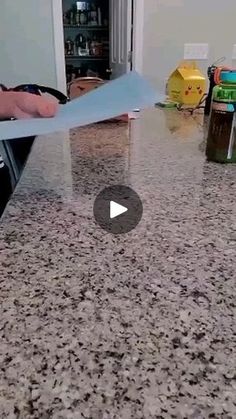 a person holding a piece of paper on top of a granite countertop in a kitchen