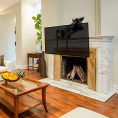 a living room filled with furniture and a flat screen tv mounted on the wall above a fire place