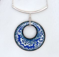 a blue and white necklace with a circular pendant hanging from it's back end