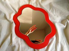 a mirror that is sitting on top of a white sheet with someone's hand in it