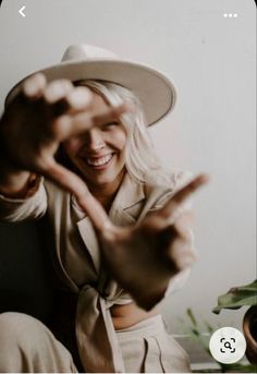 a woman wearing a white hat sitting on top of a wooden table next to a potted plant