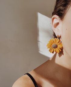 a close up of a person wearing earrings with a sunflower on it's ear