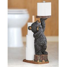 a statue of a bear holding up a sign on top of a toilet paper dispenser