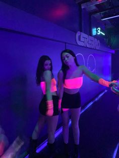 two women in neon outfits are standing near a wall