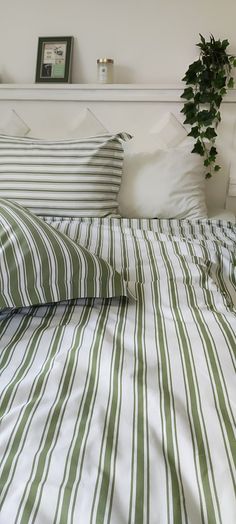 an unmade bed with green and white striped sheets