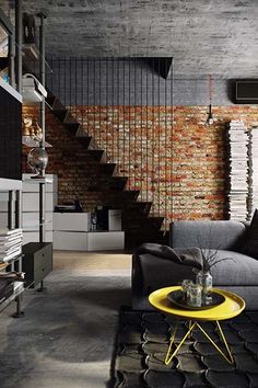 a living room filled with furniture next to a brick wall and stairs in the background