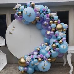 the balloon arch is decorated with flowers and butterflies