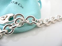 Offered for sale is a wonderful and super pretty Tiffany and Co. Sterling Silver 18K Gold Heart Key Hole Charm bracelet. The piece is made from substantial and bright Tiffany silver, and yet retains a very feminine feel to it. Attached to its very substantial and bright Tiffany Silver charm bracelet is a super pretty Heart Key Hole charm! The Heart charm has a Tiffany & Co circle clasp that opens and closes, and thus can be used as a charm on a necklace or as part of another charm bracelet! Supe Luxury White Gold Chain Bracelet With Sterling Silver Clasp, Luxury Chain Bracelet With Sterling Silver Clasp As Gift, Luxury Sterling Silver Oval Link Bracelet Gift, Designer Silver Chain Bracelet As Gift, Designer Silver Chain Bracelet For Gift, Elegant Silver Bracelet With Hallmarks, Designer Sterling Silver Bracelet As Gift, Designer Sterling Silver Bracelet For Gift, Luxury Sterling Silver Chain Bracelet As Gift