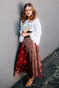 a woman leaning against a wall with her hands on her hips and looking at the camera