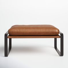 a brown leather bench sitting on top of a metal frame