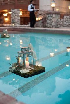 a candle is placed in the middle of a pool with flowers and candles around it