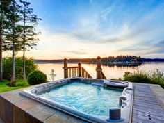 a hot tub sitting on top of a wooden deck next to a body of water