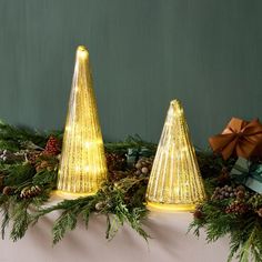 two gold christmas trees sitting on top of a mantle