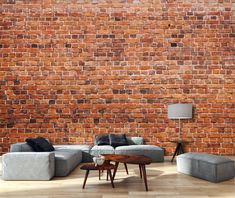 a living room filled with furniture and a large brick wall behind the couches is a coffee table